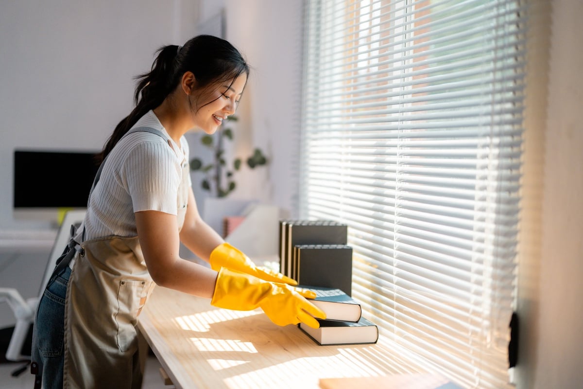 Housekeeper cleaning a wooden table wearing yellow gloves