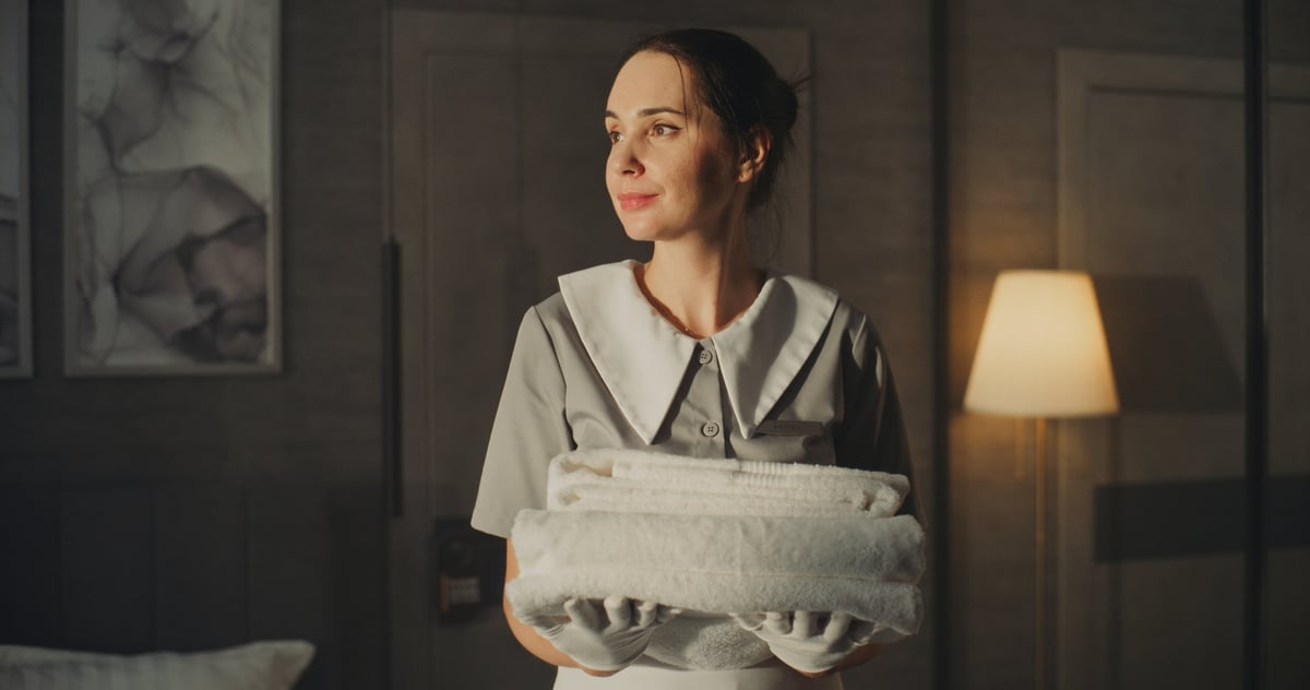 Housekeeper in uniform holding clean folded towels