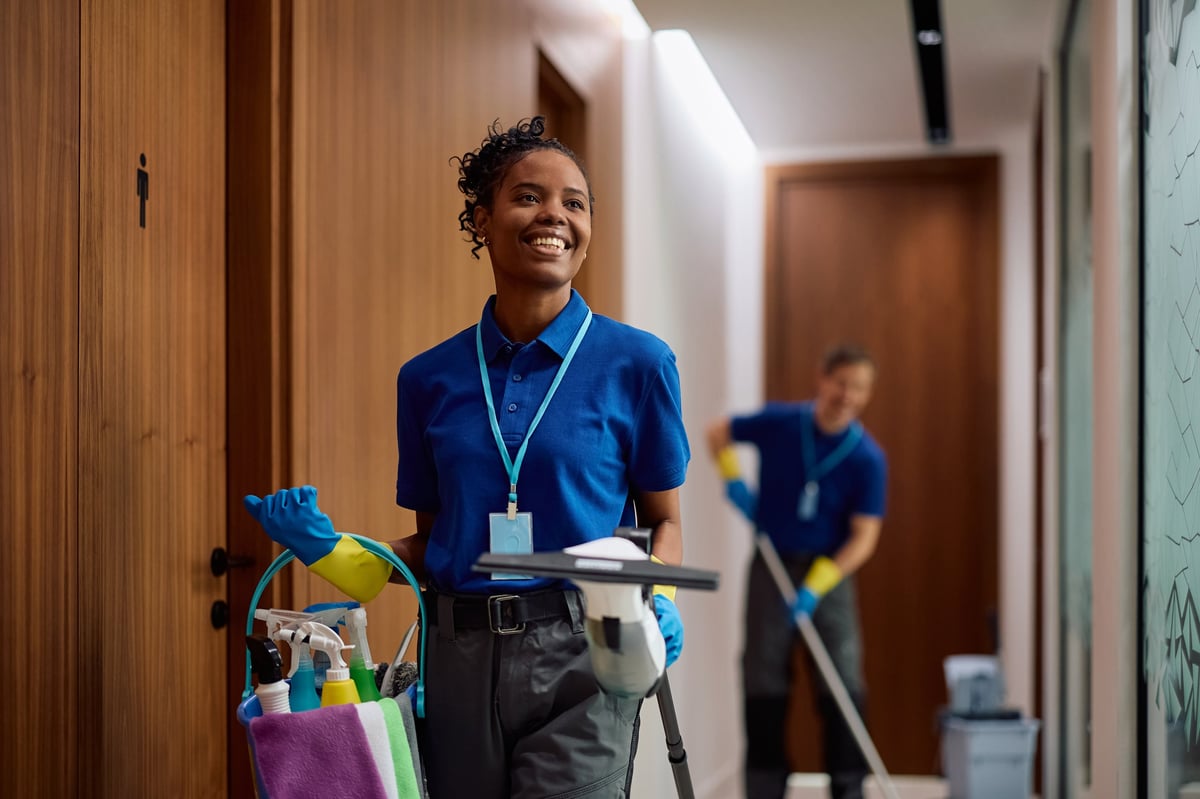Facilities maintenance professional with cleaning supplies in an office hallway